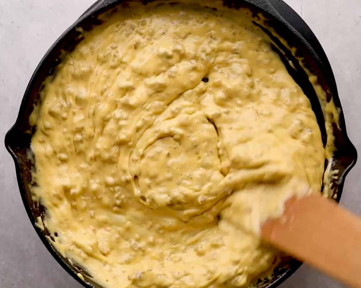 Stirring melted Velveeta cheese in a skillet until smooth and creamy for loaded cowboy queso