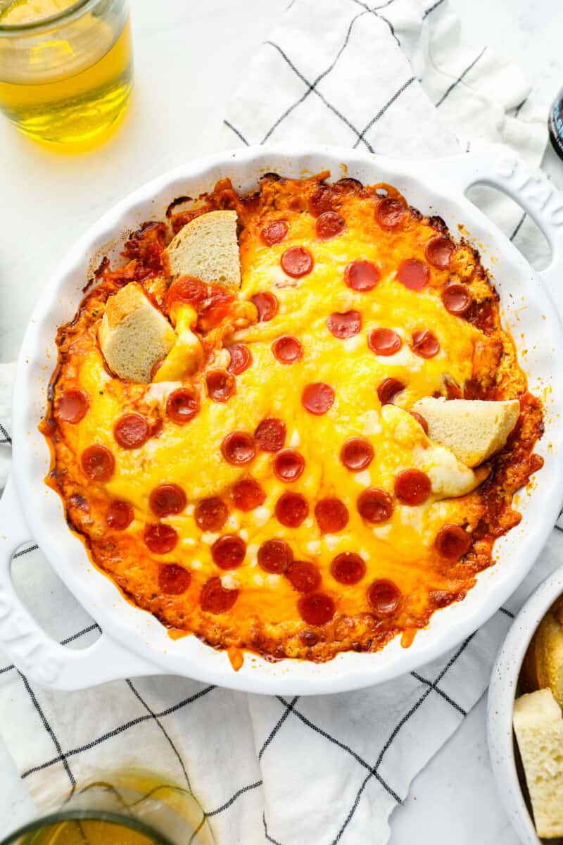 overhead view of pizza dip in a white round baking dish with 3 cubes of bread in it.