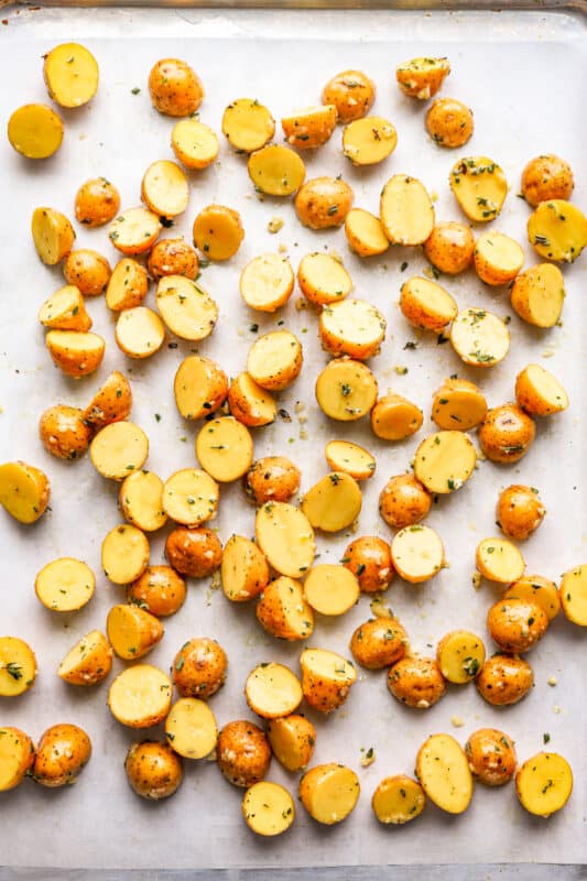 overhead view of raw halved potatoes on a baking sheet.