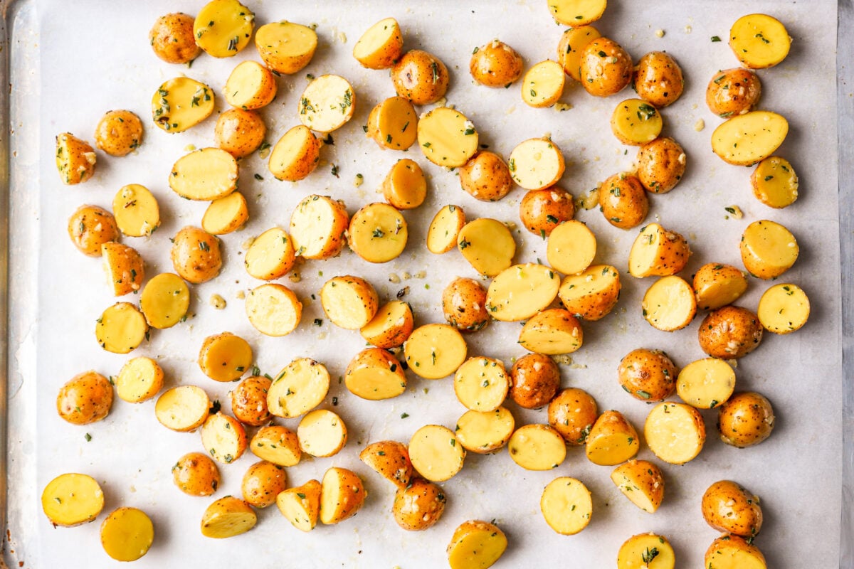 overhead view of raw halved potatoes on a baking sheet.