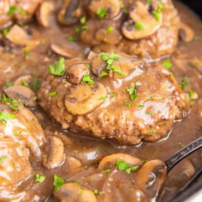 close up of salisbury steaks in a cast iron pan.
