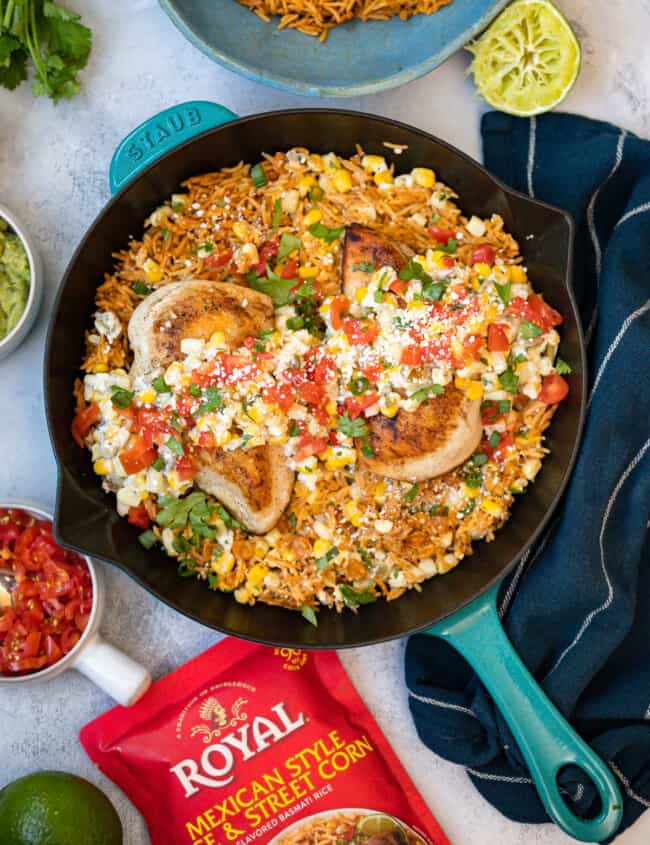 overhead view of Mexican street corn chicken in a blue cast iron skillet next to a bag of Royal rice.