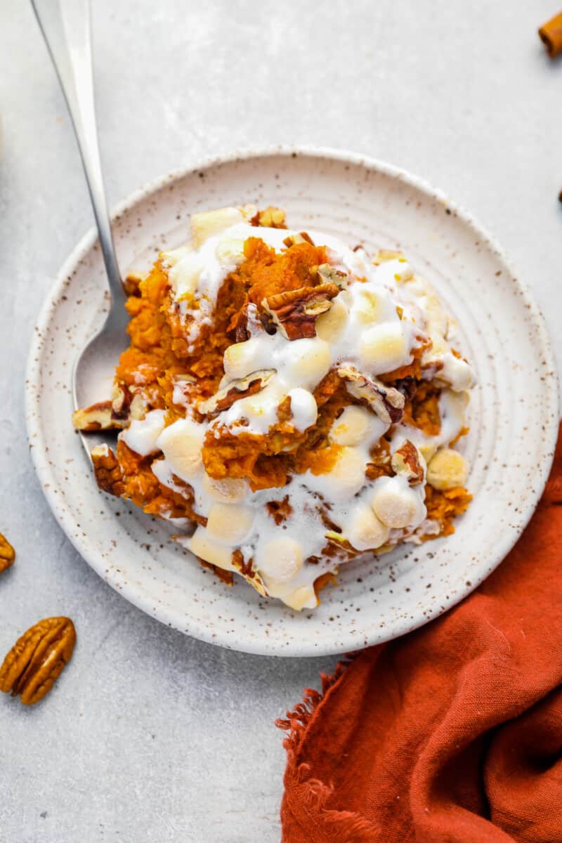 a scoop of sweet potato casserole on a white plate with a spoon.