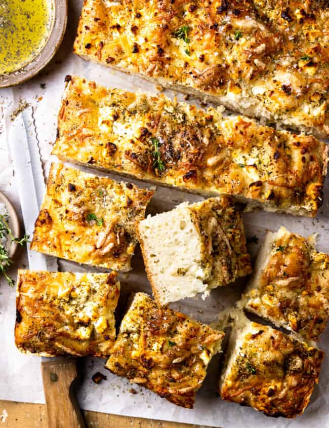 overhead view of no knead focaccia cut into squares with one upturned to show the texture.