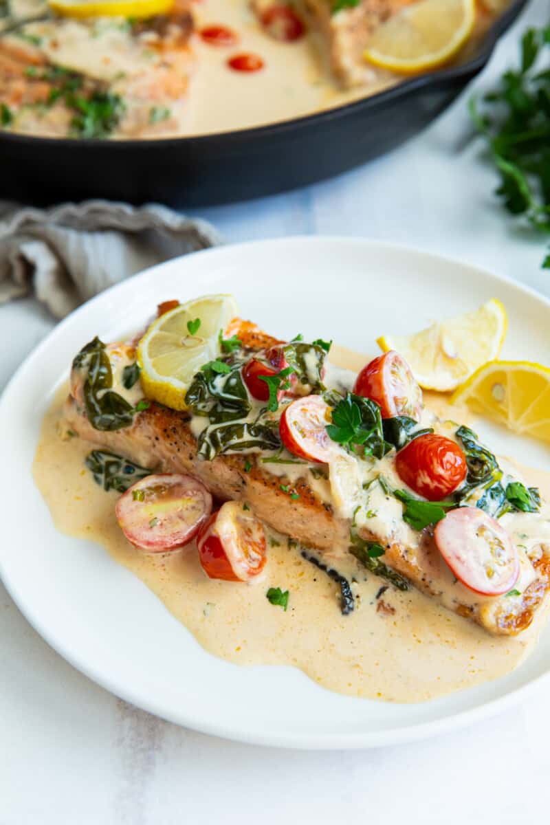three-quarters view of a filet of tuscan salmon on a white plate.