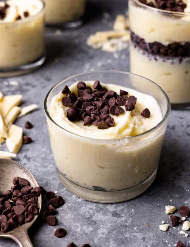 swirled white chocolate mousse in a small glass cup with chocolate chips on top.