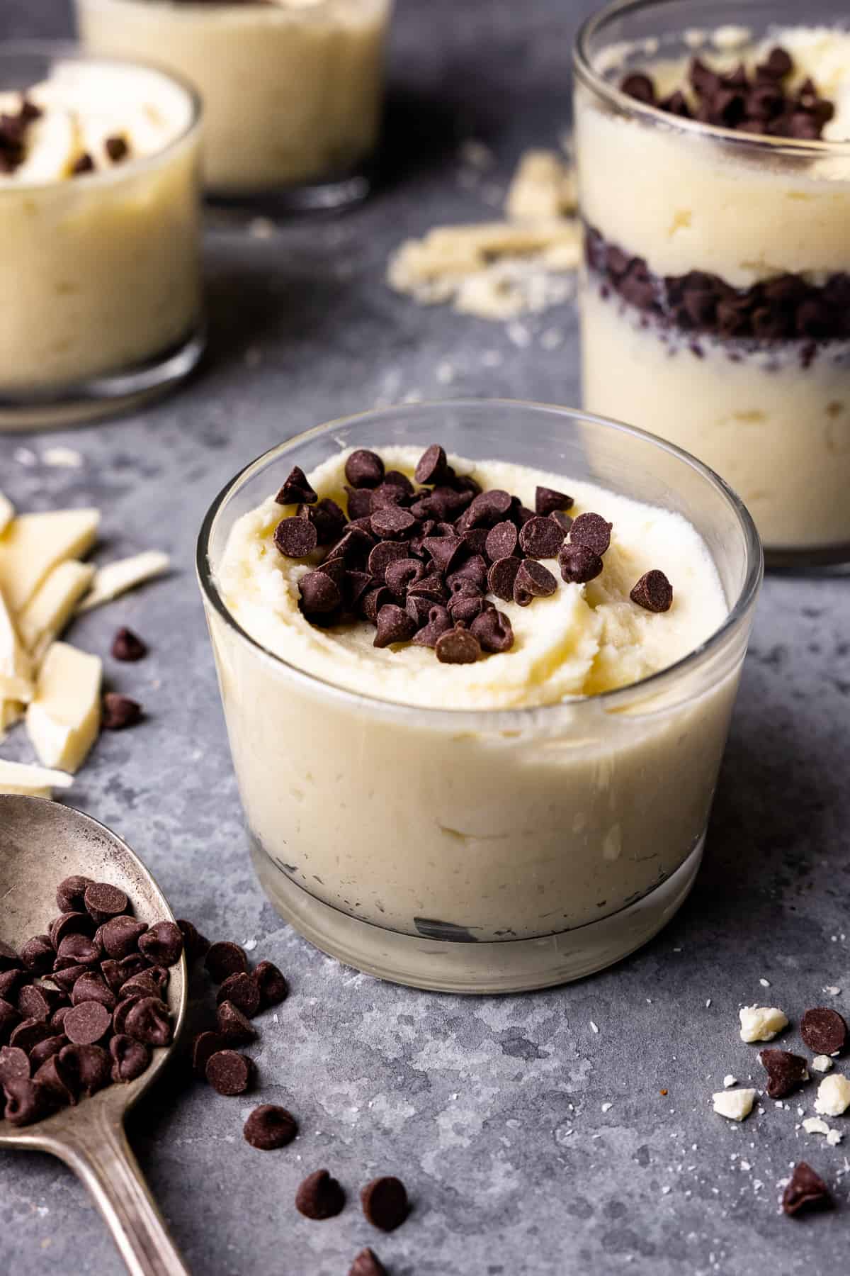 swirled white chocolate mousse in a small glass cup with chocolate chips on top.