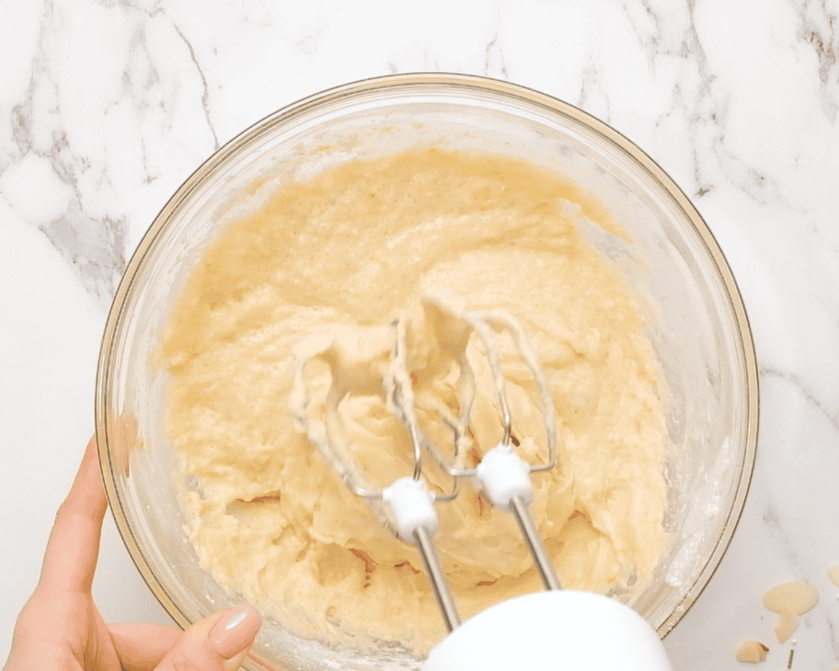 Beating wet and dry ingredients with an electric beater.