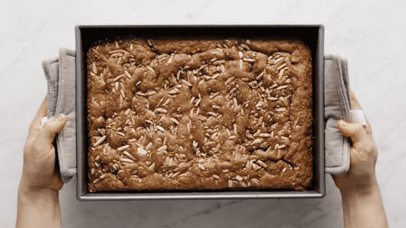 A person holding a coffee cake in a box.