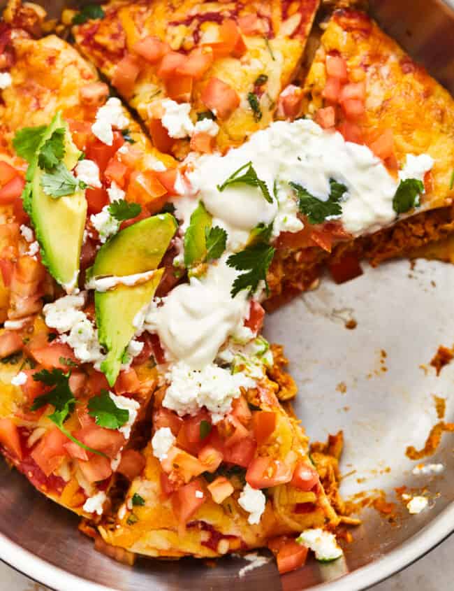 overhead view of a sliced chicken enchilada skillet in a skillet missing a slice.