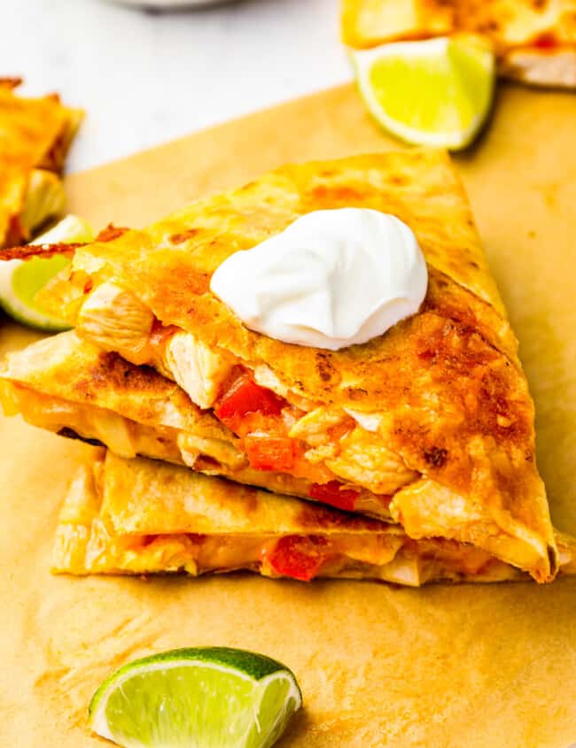 3 stacked slices of chicken quesadilla on parchment paper.