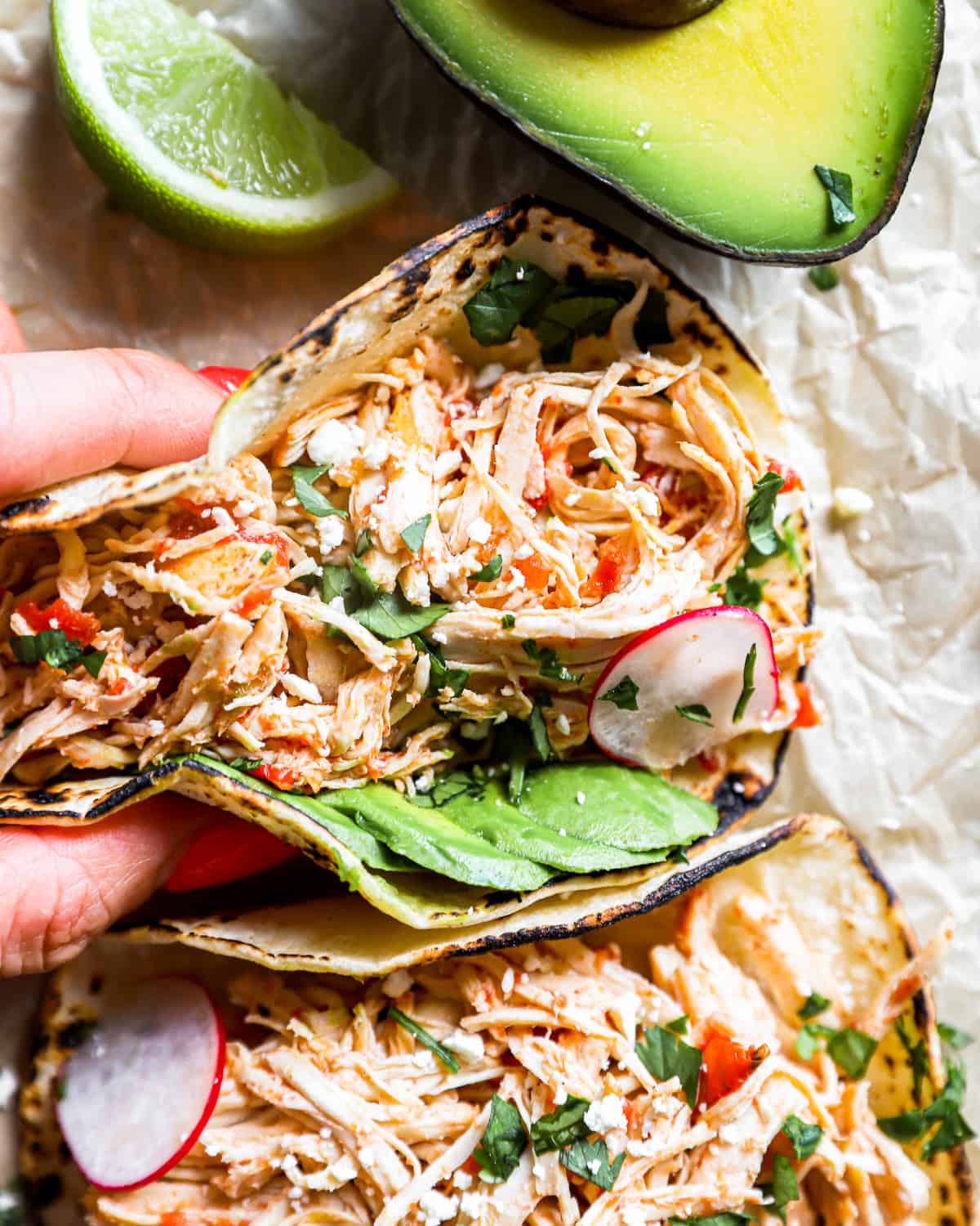 overhead view of a hand grabbing a crockpot chicken taco