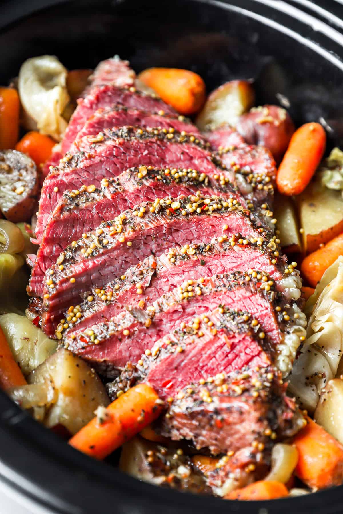 close up overhead view of sliced crockpot corned beef and cabbage in a crockpot.