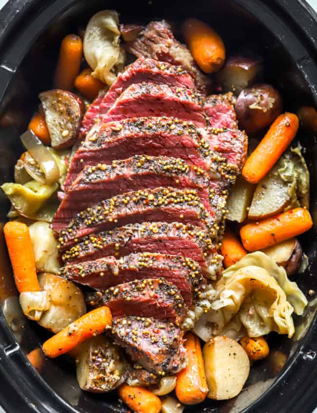 overhead view of sliced crockpot corned beef and cabbage in a crockpot.