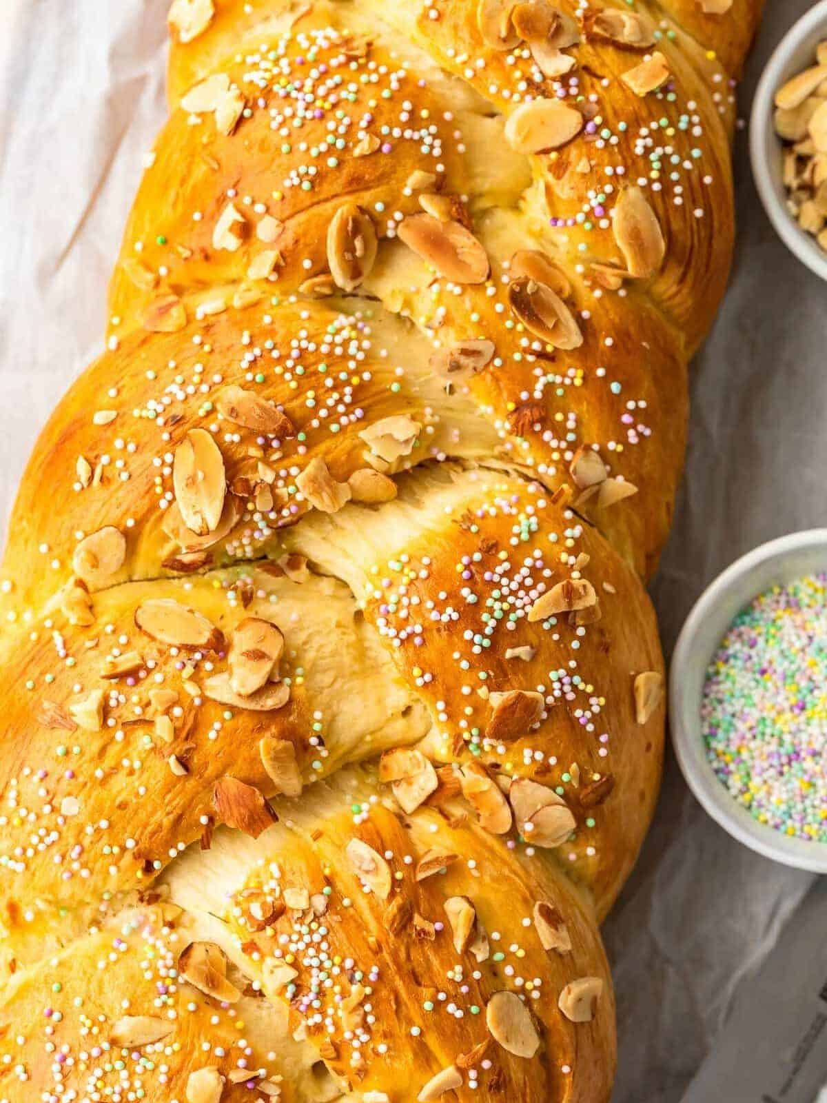 a loaf of braided easter bread topped with almonds and pastel-colored sprinkles