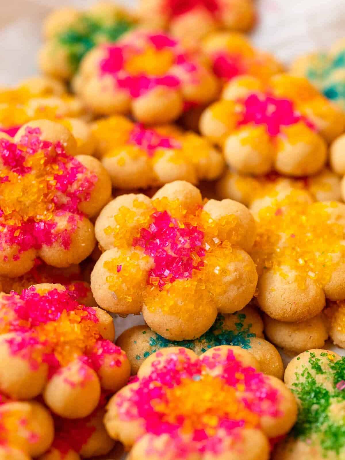 close up of flower-shaped spritz cookies decorated with brightly colored sprinkles.