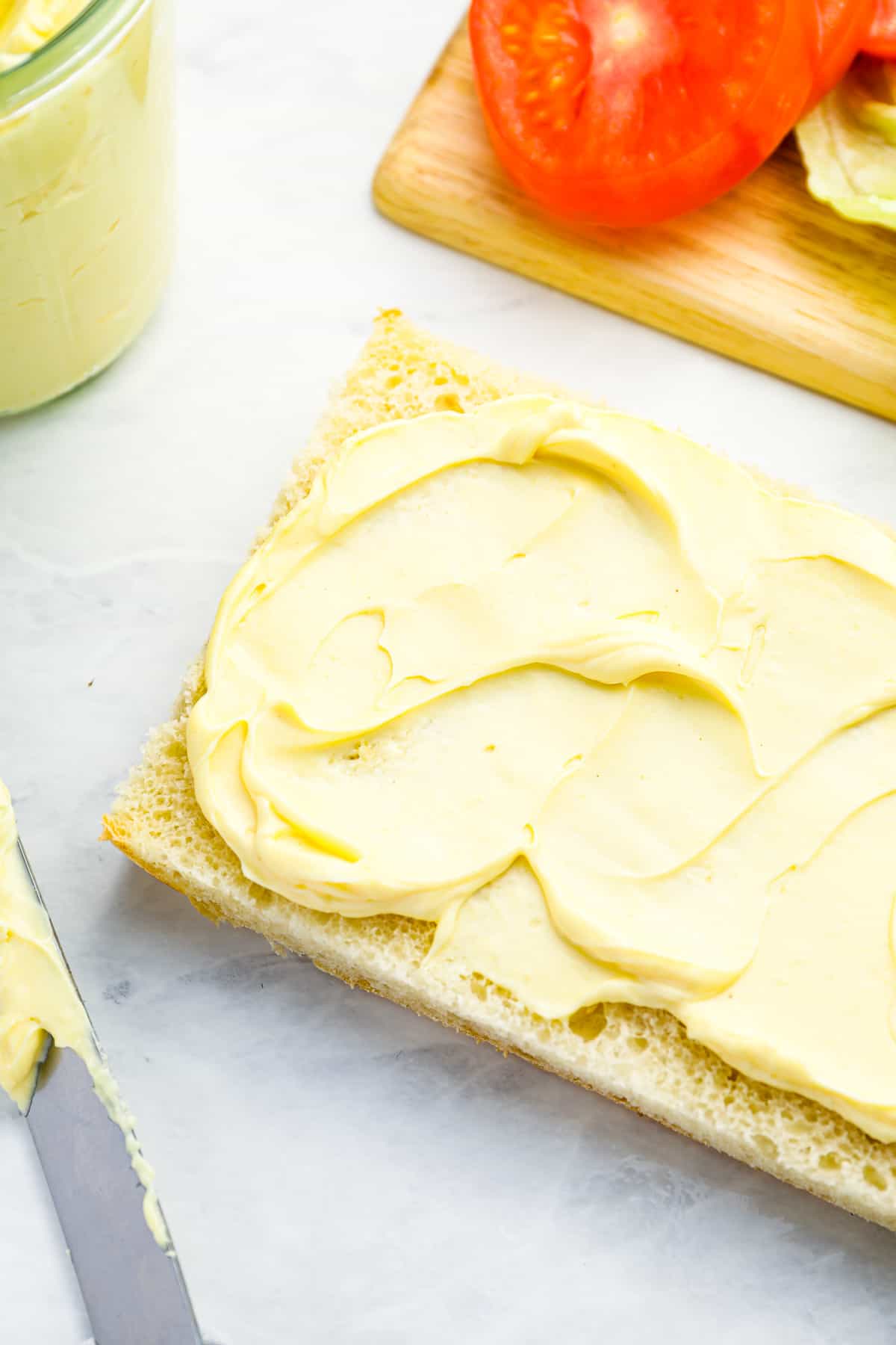 overhead view of mayonnaise slathered on a piece of ciabatta bread.