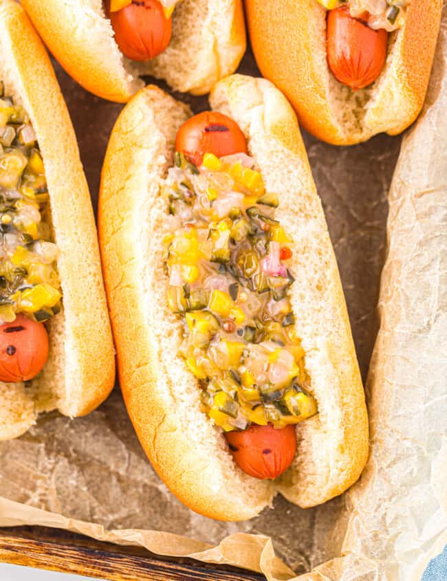 close up overhead view of a hot dog topped with pickle relish in a baking pan.