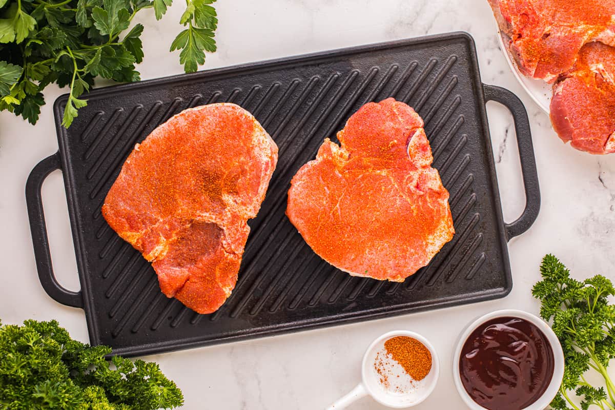 Overhead view of 2 pork chops on a rectangular grill pan.