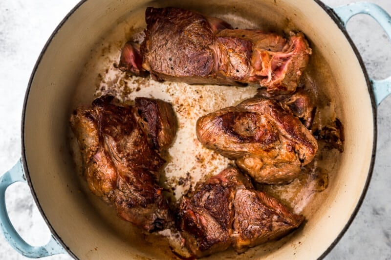 braised meat in a blue and white dutch oven.