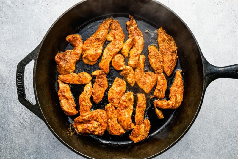 cooked chicken pieces in a cast iron skillet.