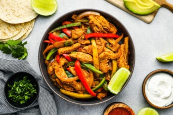 chicken fajita filling in a black bowl with a lime wedge.