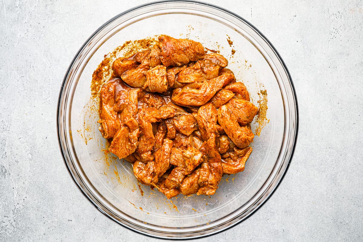 Marinated chicken pieces in a glass bowl.