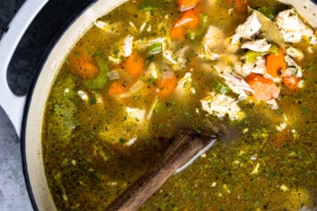 overhead view of homemade chicken noodle sop in a dutch oven with a wooden spoon.