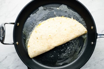 a folded chicken quesadilla in a frying pan.