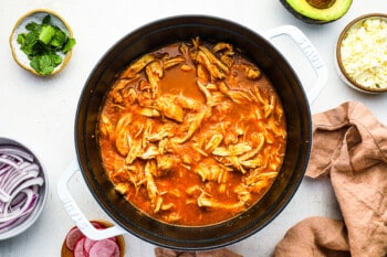 shredded chicken mixed into tinga sauce in a dutch oven.