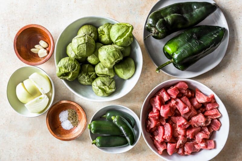 overhead view of ingredients for chile verde in individual bowls.