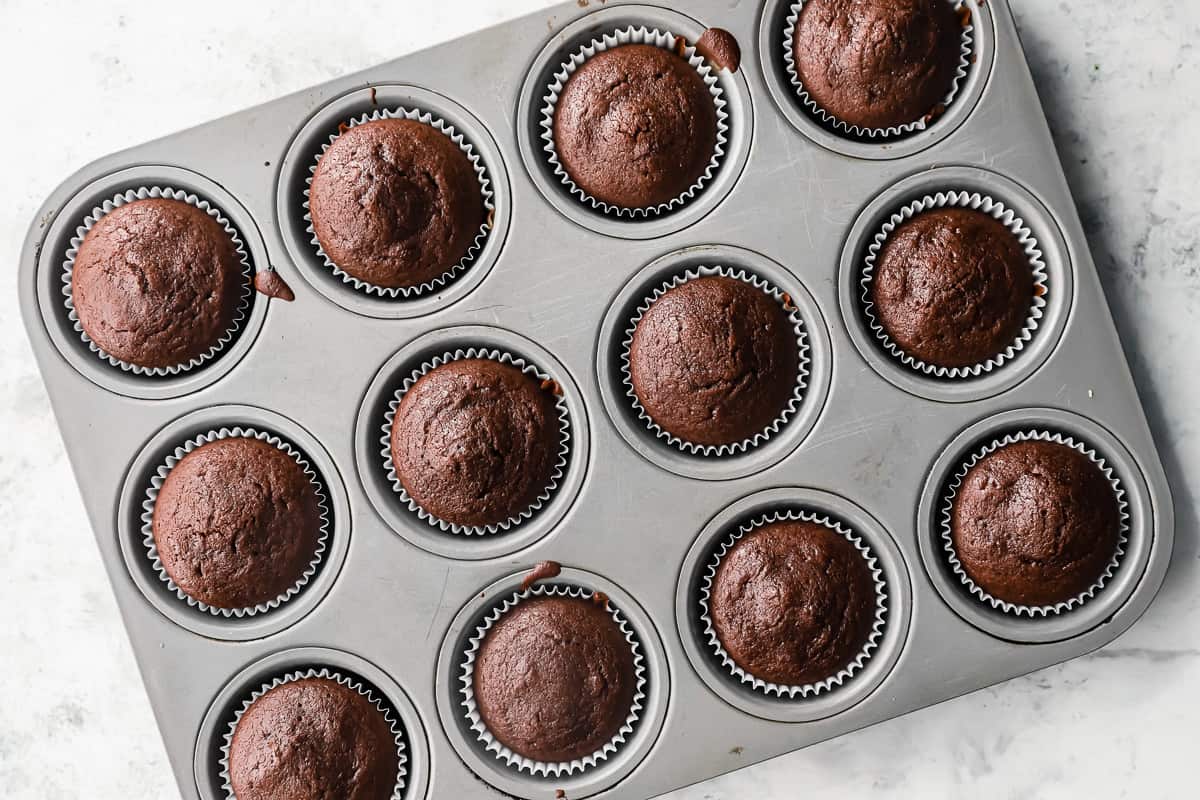 overhead view of 12 baked chocolate cupcakes in a cupcake tin.