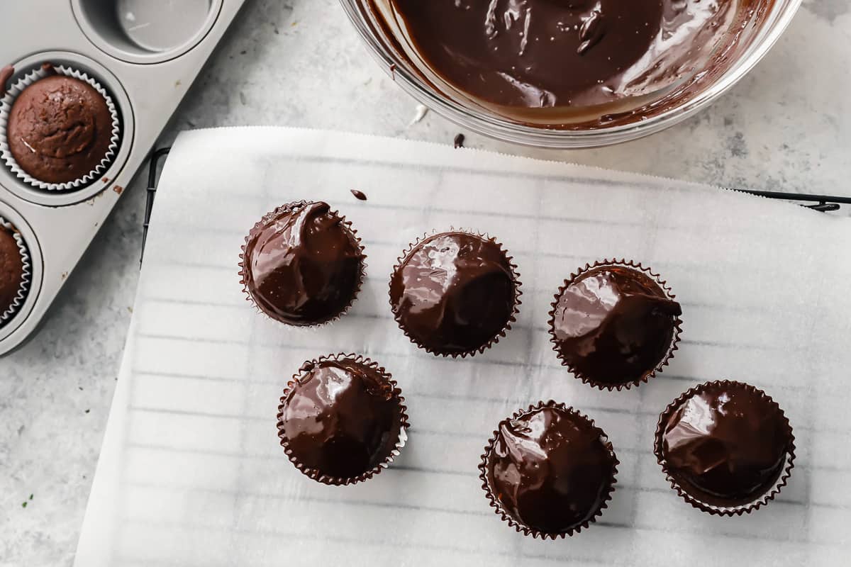 overhead view of 6 ganache-dipped hostess cupcakes on parchment paper.