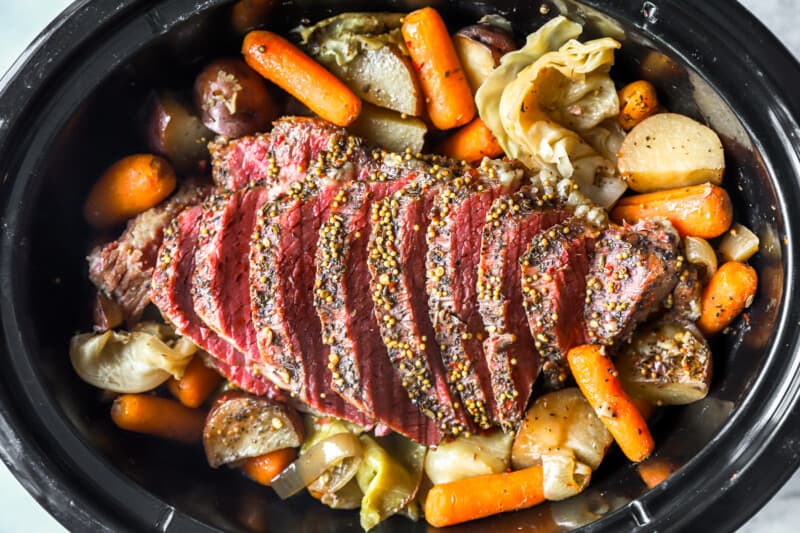 sliced crockpot corned beef and cabbage in a crockpot.