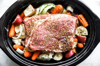 whole uncooked crockpot corned beef and cabbage in a crockpot.