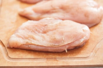 a raw chicken breast sliced to make a pocket on a cutting board.