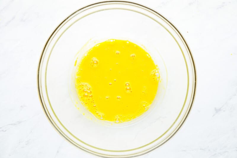 whipped egg yolks, mustard, and vinegar in a glass bowl.