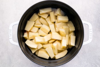 2-inch pieces of potato in a white and black dutch oven.