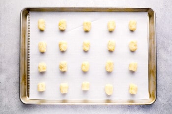 20 shaped tater tots on a parchment-lined baking sheet.