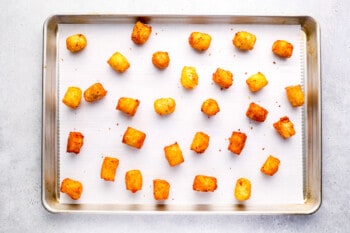 fried tater tots on a parchment-lined baking sheet.
