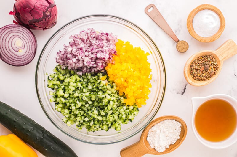 chopped cucumber, onion, and pepper in a glass bowl.