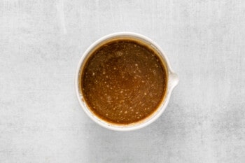 a bowl of brown sauce on a white surface.