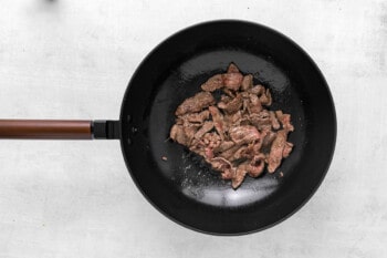 a wok with meat in it on a white background.