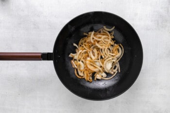 fried onions in a wok on a white background.