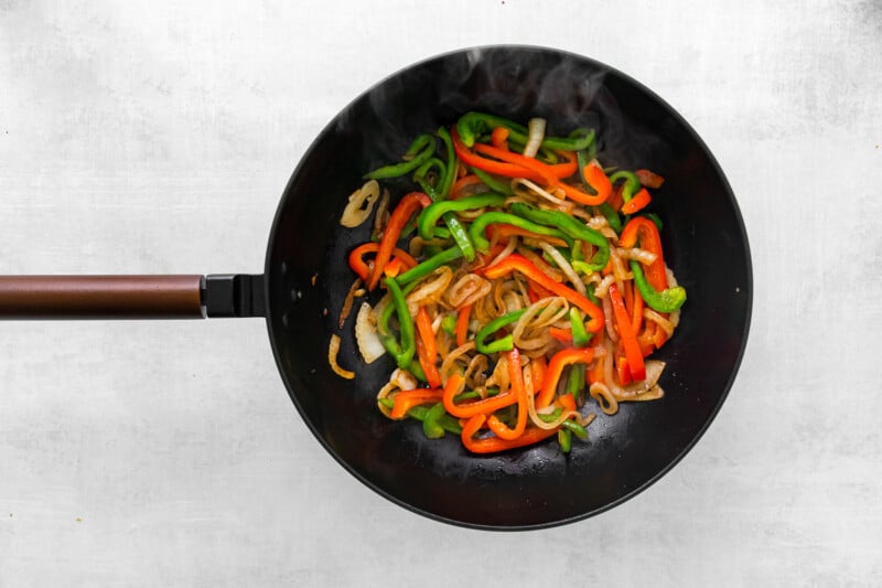 stir fried vegetables in a wok on a white background.