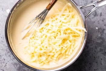 cheesy sauce in a pan with a whisk.