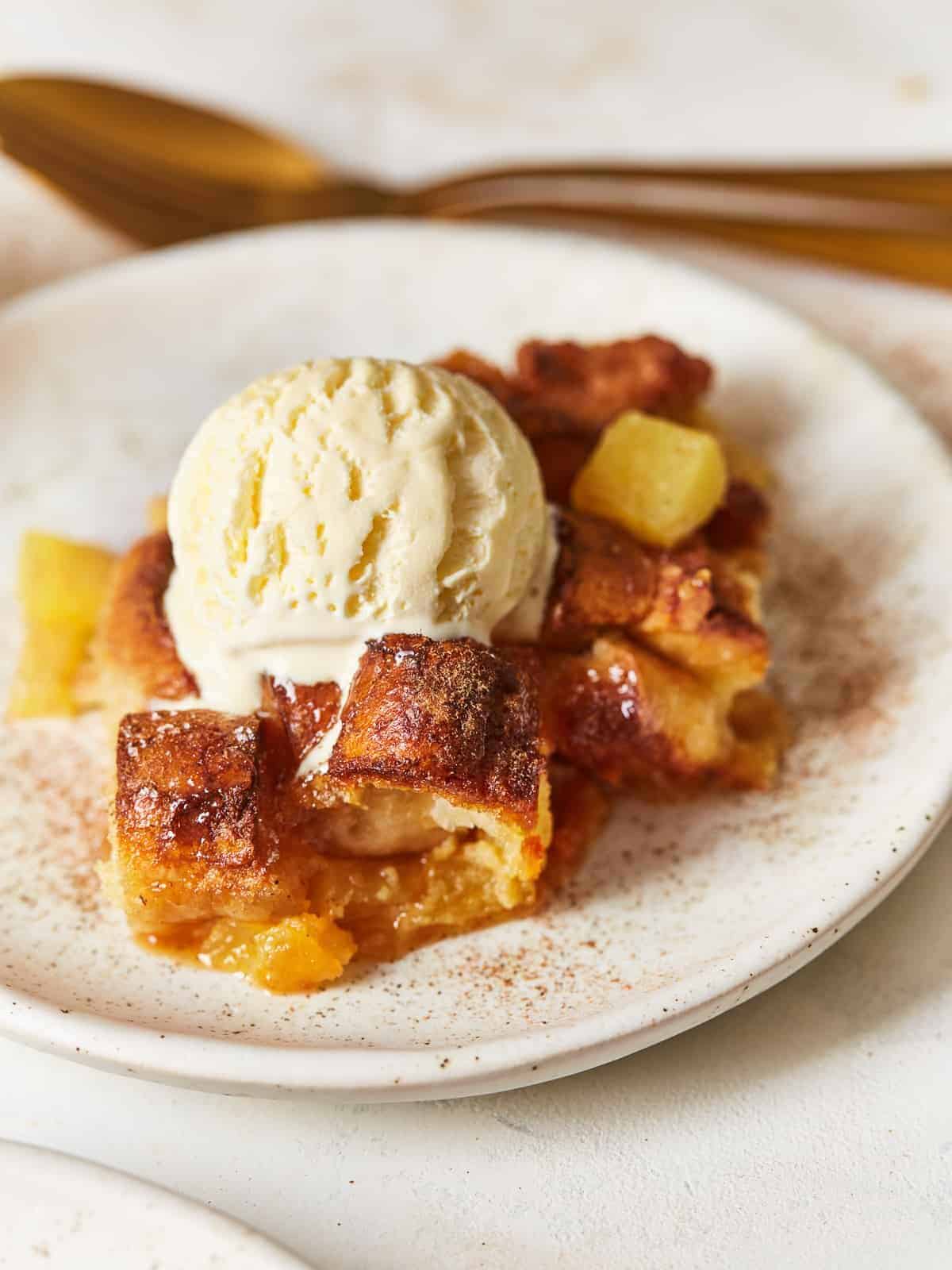 a plate of bread pudding with pineapple and a scoop of vanilla ice cream