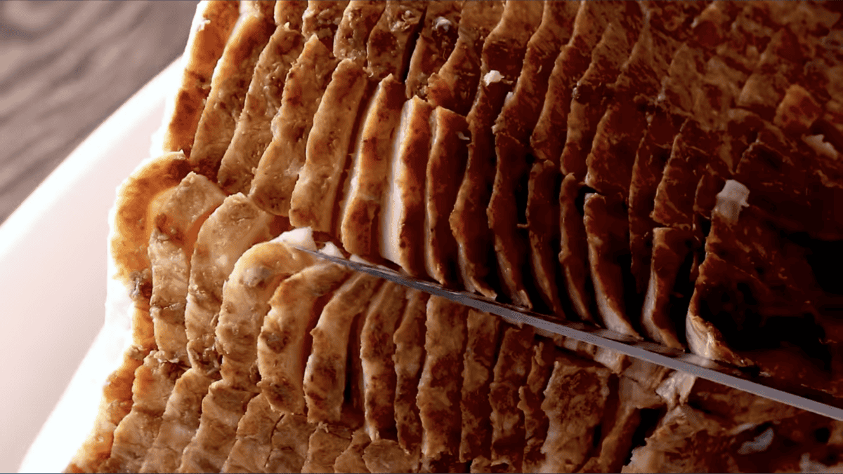 a knife cutting a spiral ham.