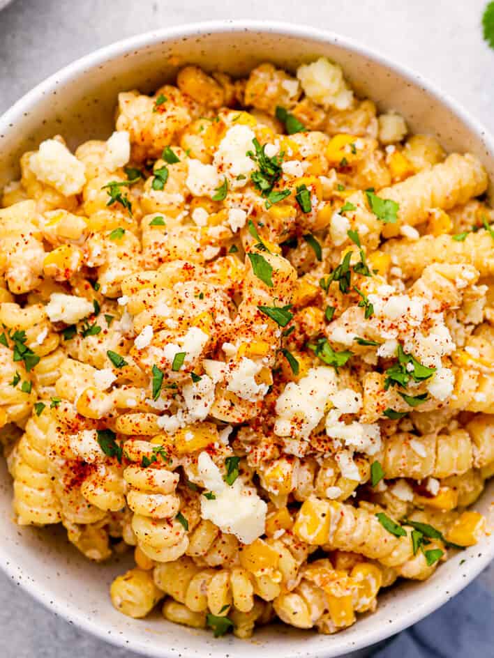 overhead view of a serving of street corn pasta salad in a white bowl.