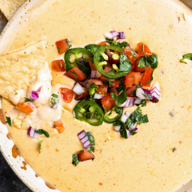 a bowl of cheesy dip with chips and salsa.